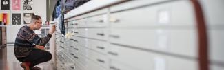 A person labels a drawer of archival items in the Audain Gallery at UBC